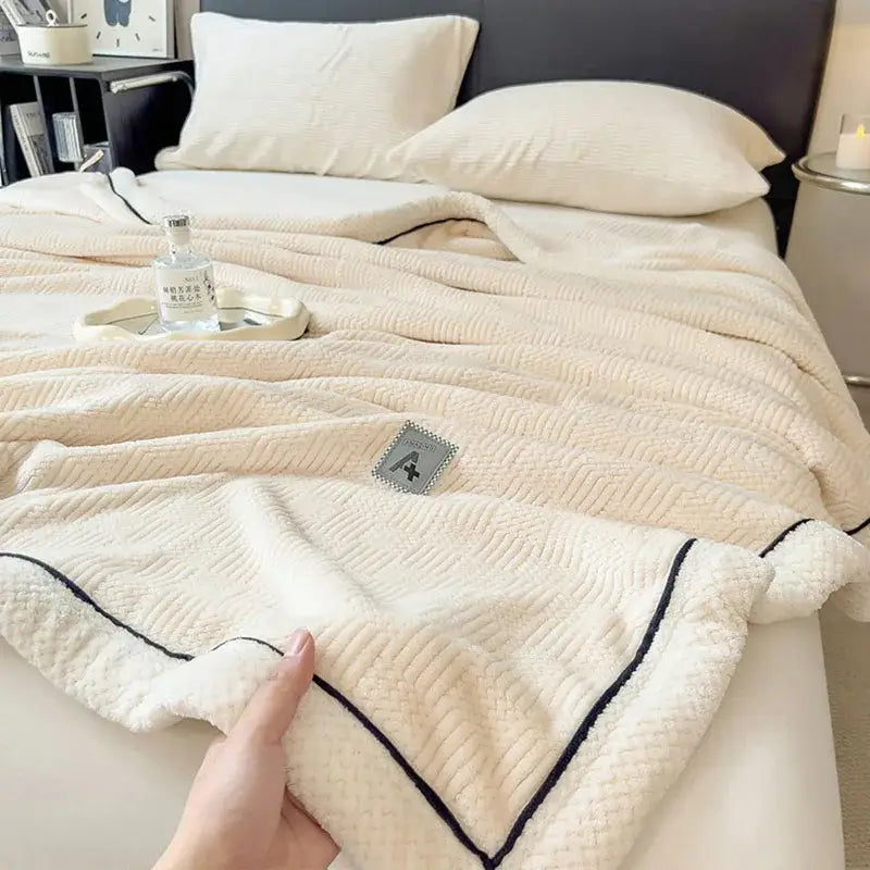Cream-colored cozy striped knitted velvet bedroom blanket with black stitched trim and gray patch label decorbites cozy striped
