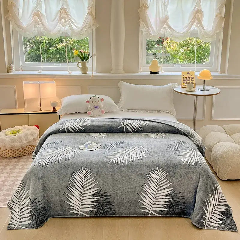 Gray plush blanket with white and black palm leaf pattern contrasting with cozy white fleece blanket with colorful flower patterns