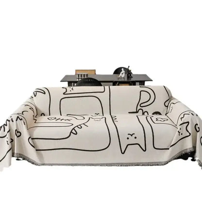 Cream-colored chenille sofa cover with black line-drawn cartoon cat patterns and fringed edge for living room