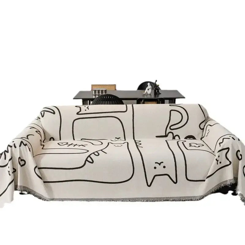 Cream-colored chenille sofa cover with black line-drawn cartoon cat patterns and fringed edge for living room
