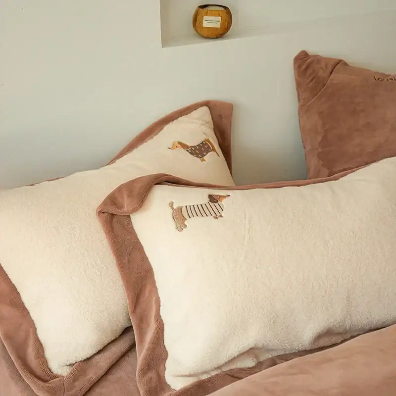 Cream-colored plush pillowcases with embroidered dachshund design and dusty rose velvet trim in an embroidered imitation cashmere bedding set
