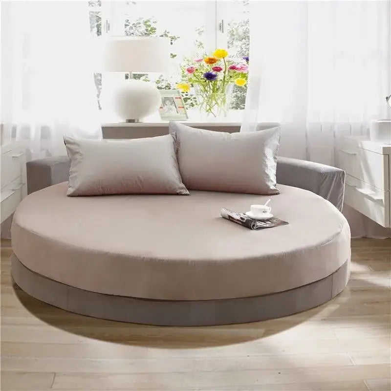 Beige round daybed with plush cushioning and soft fabric cover paired with cream and gray fitted bed sheet set