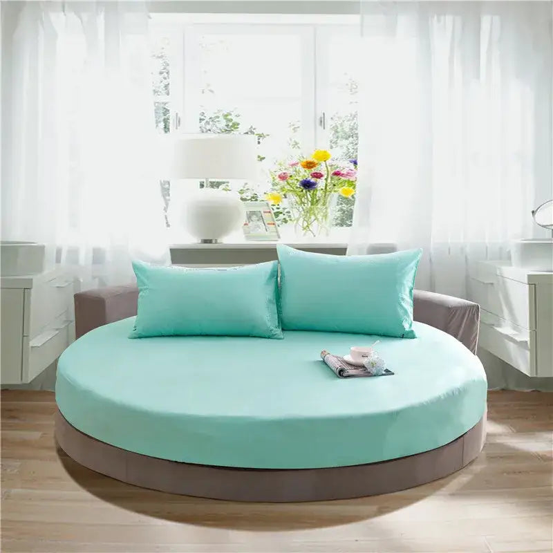 Cream and gray round fitted bed sheet set on a circular bed with a soft mint green mattress and matching pillows