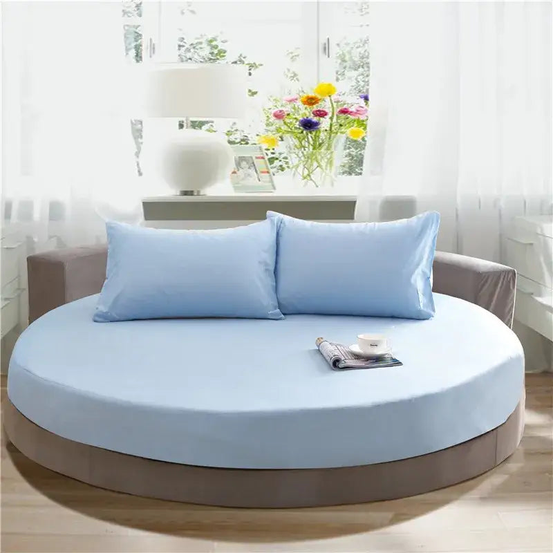 Light blue round fitted bed with matching pillowcases and brown upholstered base in cream and gray bed sheet set