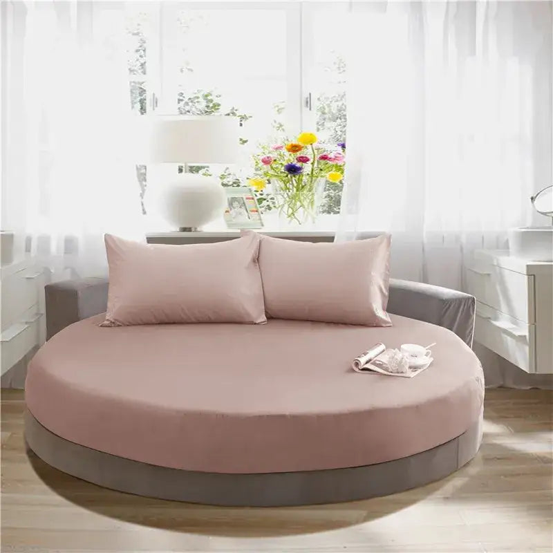 Cream and gray round fitted bed sheet set on a round bed with soft pink mattress cover and matching pillows