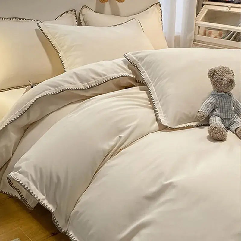 Cream-colored satin bedding set with dark gray zigzag stitching and decorbites cozy shell edges for a cozy bedroom