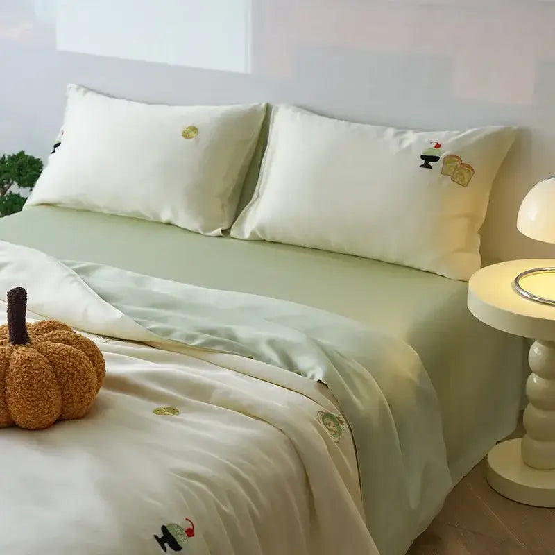 Cream-colored satin comforter set with green decorbites cartoon embroidery featuring food-themed designs