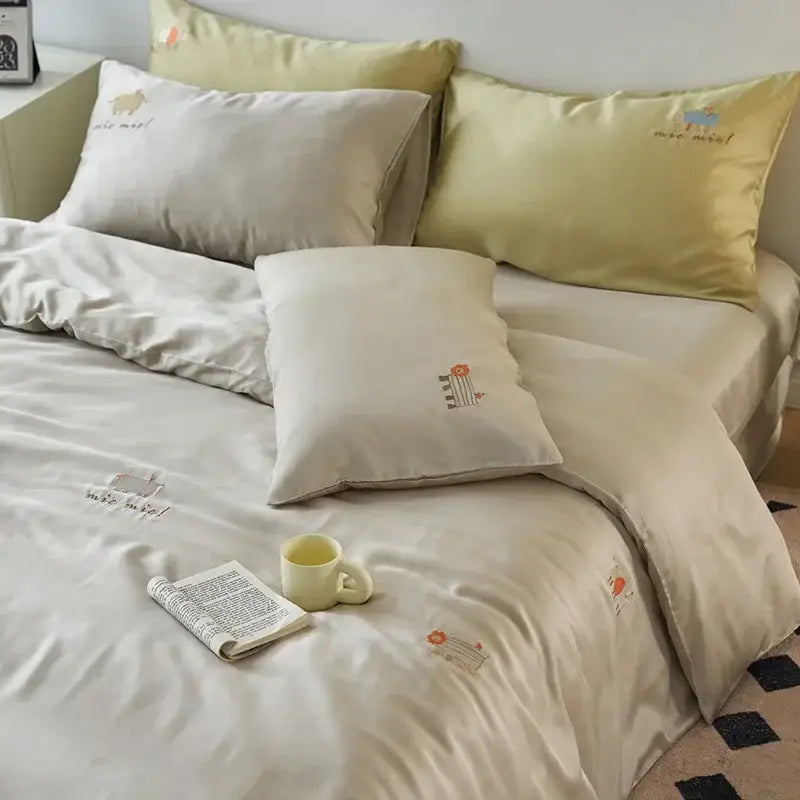 Cream and green cartoon embroidery comforter set featuring cream-colored satin bedding with embroidered animal and floral motifs