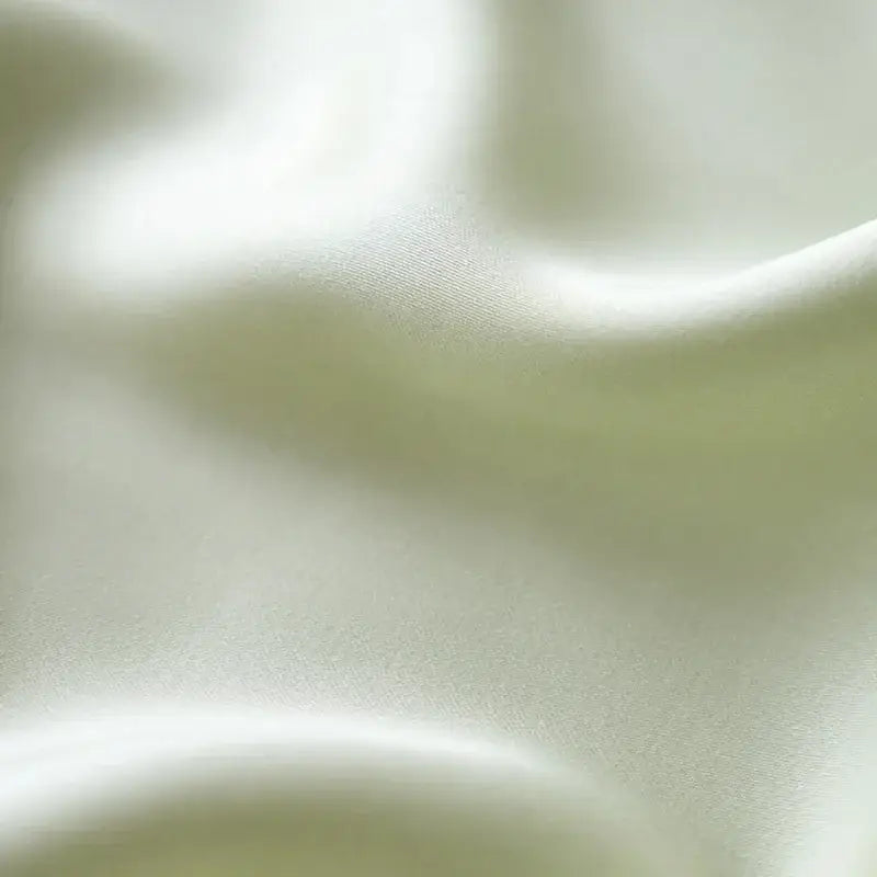 Soft creamy white silk fabric with smooth folds in cream and green cartoon embroidery comforter set by decorbites