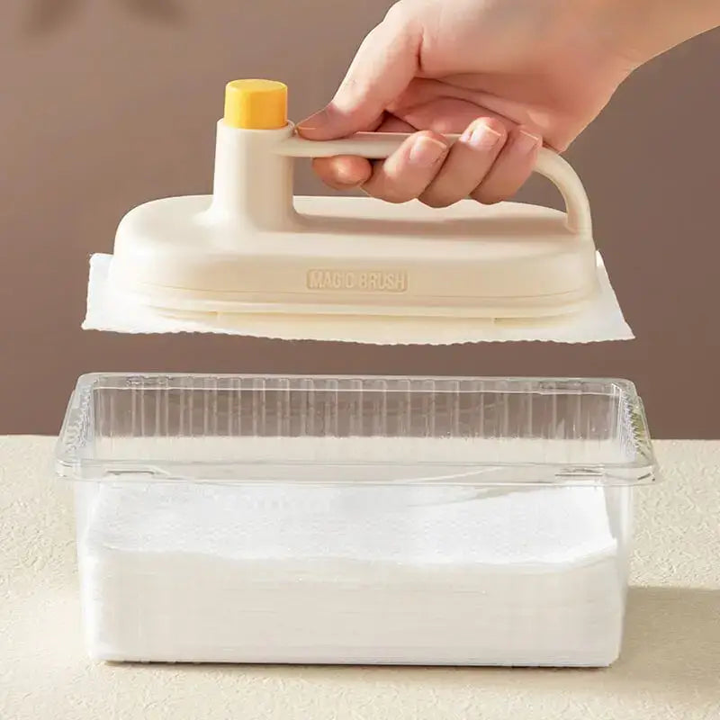 Cream-colored handheld steam iron with yellow knob and transparent tank shown alongside cream and yellow silicone kitchen cleaning brush with replaceable head