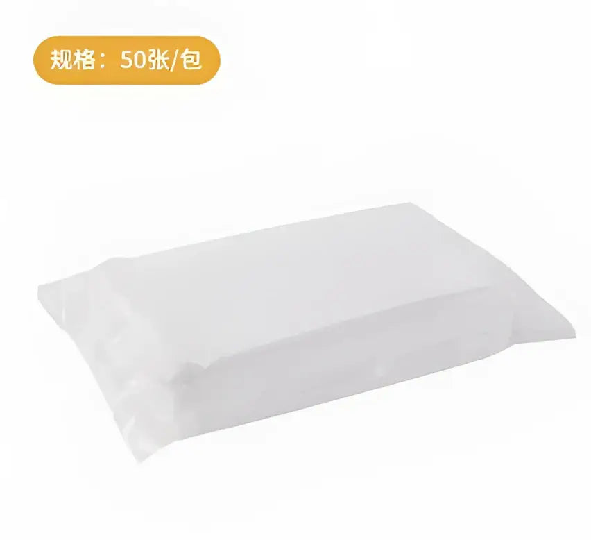 A clear plastic package containing white paper sheets alongside a cream and yellow silicone kitchen cleaning brush with replaceable head