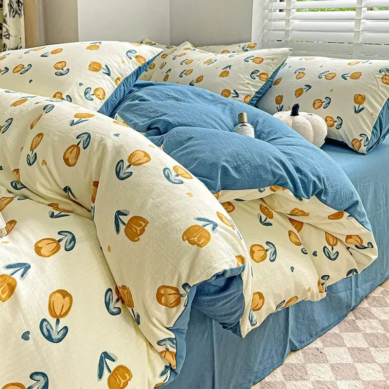 Cream-colored cartoon pattern cotton bedding set with orange tulips and teal stems layered over blue comforter