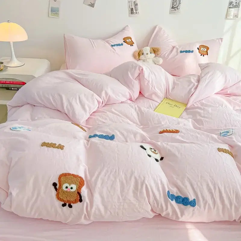 Pink quilted comforter set featuring cartoon embroidery jacquard with toast characters and blue squiggly accents for bedroom use