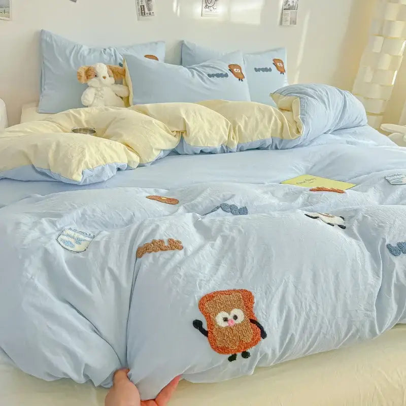 Cream cartoon embroidery jacquard comforter set in light blue and cream featuring embroidered cartoon toast characters