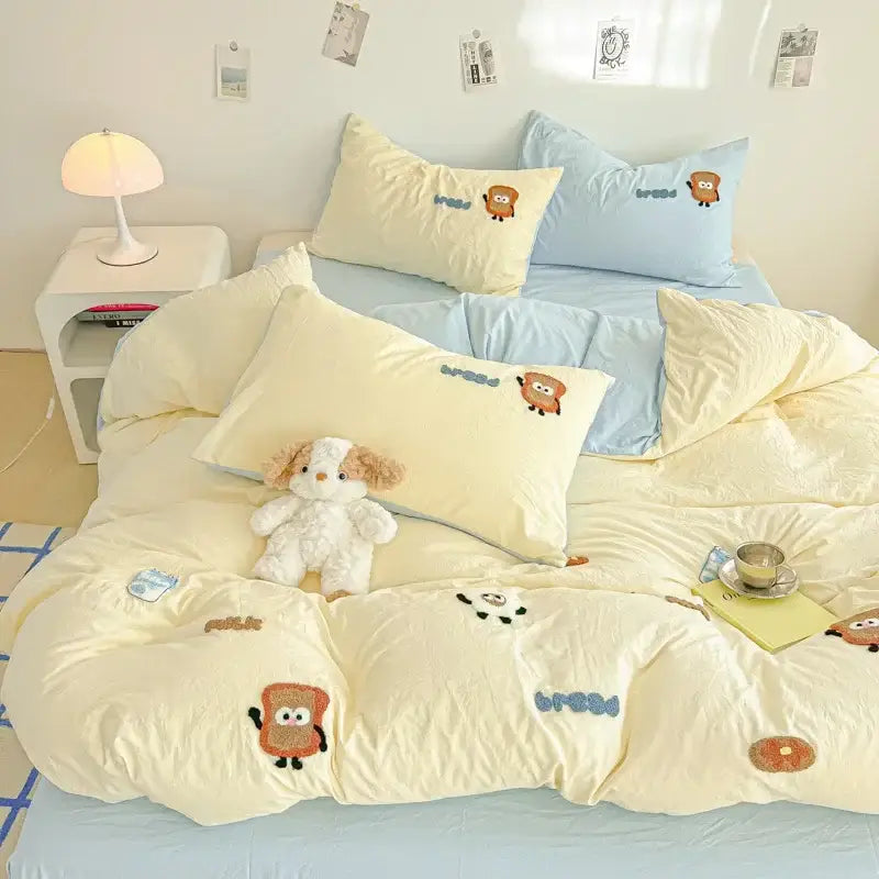 Cream-colored jacquard comforter set with cartoon embroidery featuring toast characters and blue text accents for bedroom use
