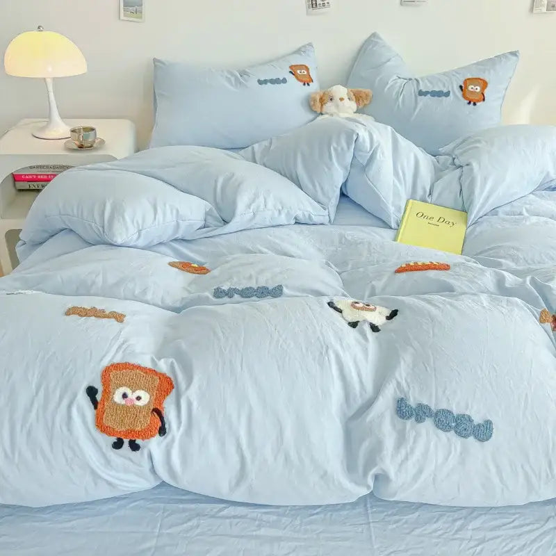 Light blue quilt set with cartoon embroidery jacquard featuring embroidered toast and bread characters in cream tones
