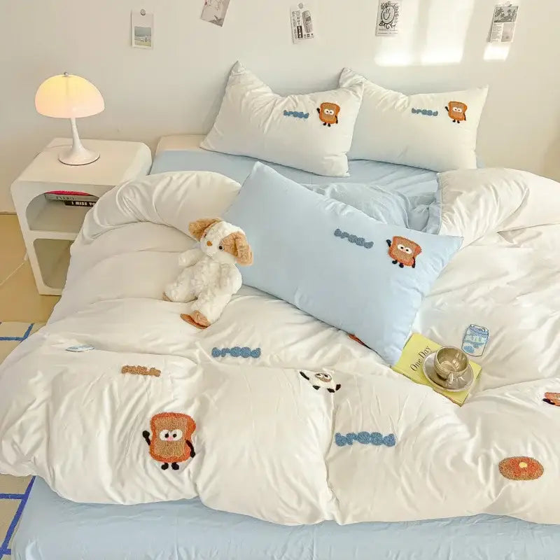 Cream cartoon embroidery jacquard comforter set with white duvet cover featuring orange and blue embroidered cartoon toast characters