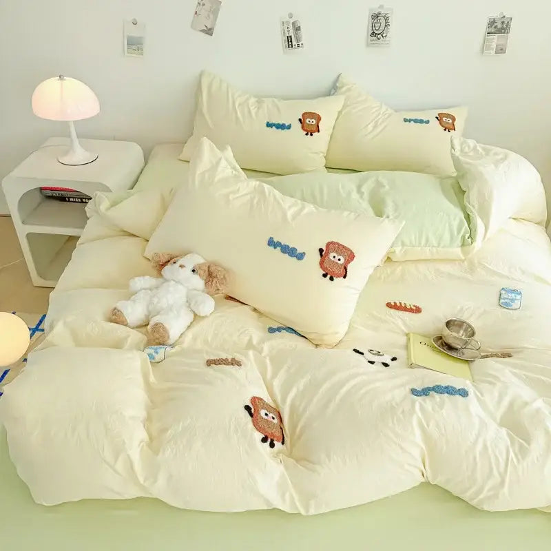 Cream cartoon embroidery jacquard comforter set featuring cream quilted bedding with embroidered toast and blue lines