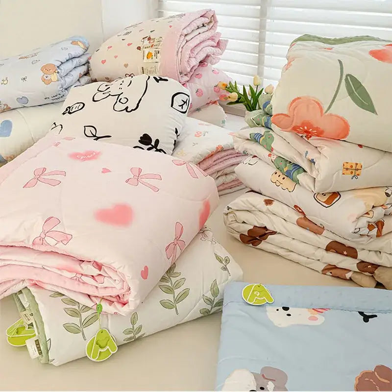 Stack of cream pastel quilted comforters with decorbites cartoon pattern summer design featuring bows hearts and animals
