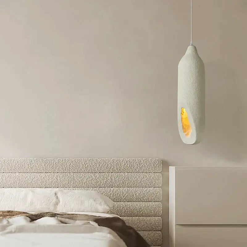 A modern cream ceramic pendant light with textured decorbites cement handmade surface and golden illuminated interior