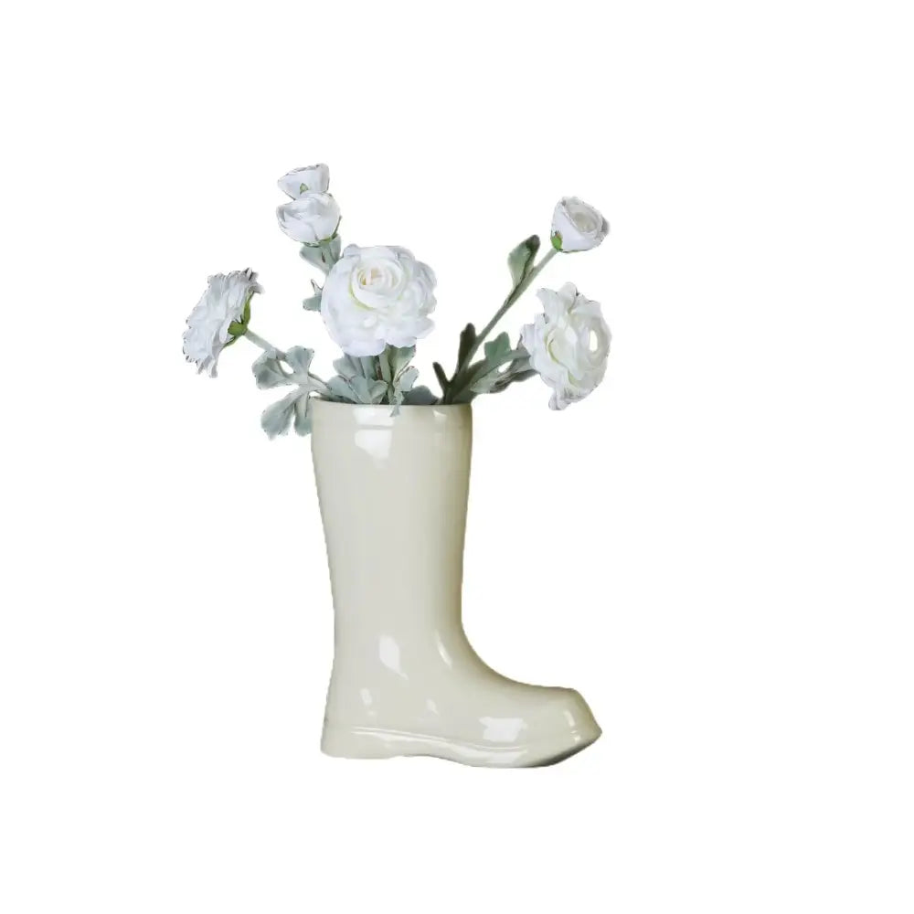 Cream ceramic shoe vase by decorbites featuring cream-colored ceramic boot shape holding white flowers decor