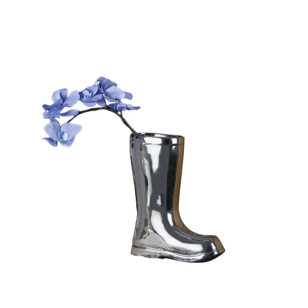 Shiny silver decorbites ceramic shoe vase shaped like a boot holding blue orchids for living room decor