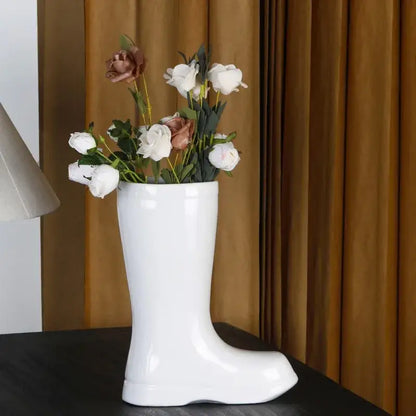 Cream ceramic shoe vase with a glossy finish holding white and rose-gold artificial roses decorbites ceramic shoe decor