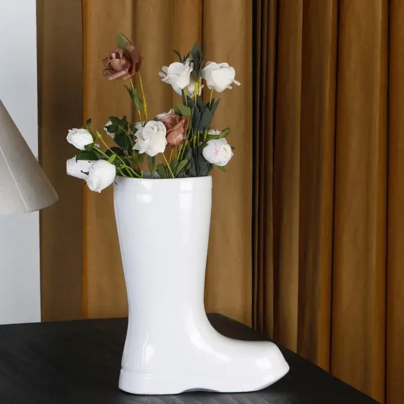 Cream ceramic shoe vase with a glossy finish holding white and rose-gold artificial roses decorbites ceramic shoe decor
