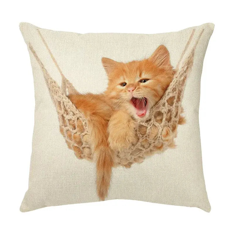 Beige linen throw pillow with cute cat face printed showing an orange kitten yawning in a crocheted hammock