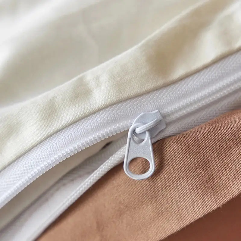 White zipper with matching pull tab on cream egyptian cotton tulip embroidery bedding set fabric close-up