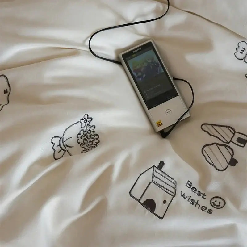Silver sony walkman with black earphones resting on cream embroidered decorbites brushed volcanic fleece bedding set