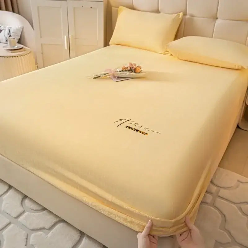Cream embroidered cozy velvet fitted sheet in soft yellow with elasticized edge and subtle embroidered logo