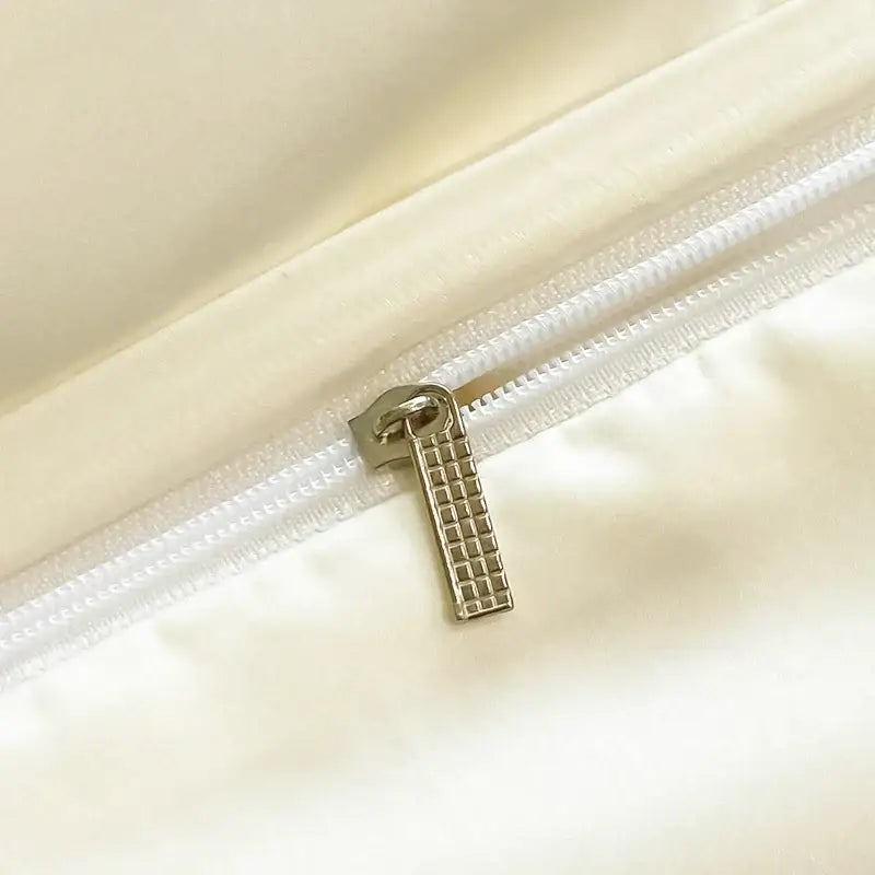 Cream embroidered ice silk bedding set with a silver-toned textured zipper pull on cream fabric