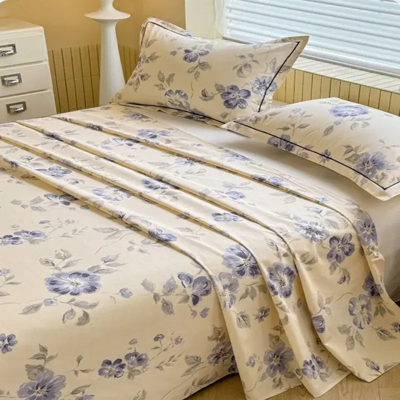 Cream flower print satin bed cover featuring cream color, delicate purple gray floral patterns, and black piping accents