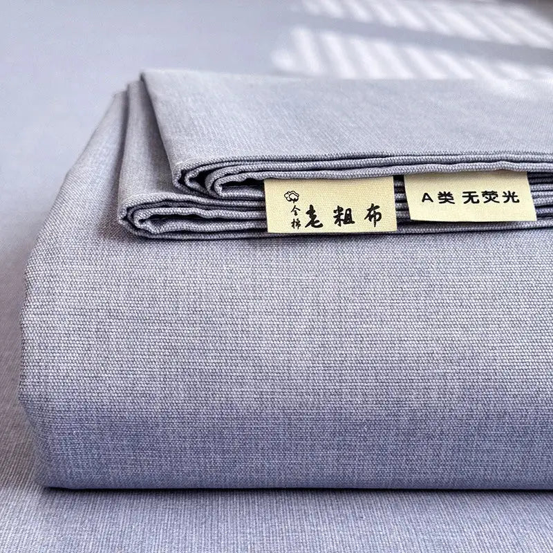 A neatly folded gray textured cotton fabric bed cover with beige labels for decorbites cooling cotton material
