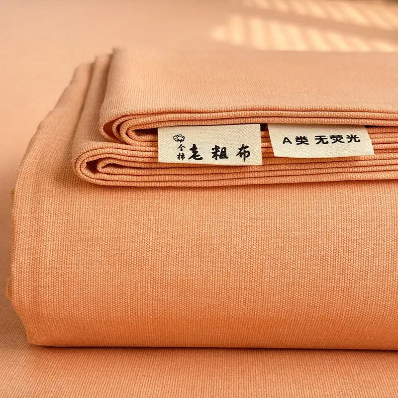 A neatly folded peach-colored cotton bed cover with textured weave and white labels for decorbites cooling cotton