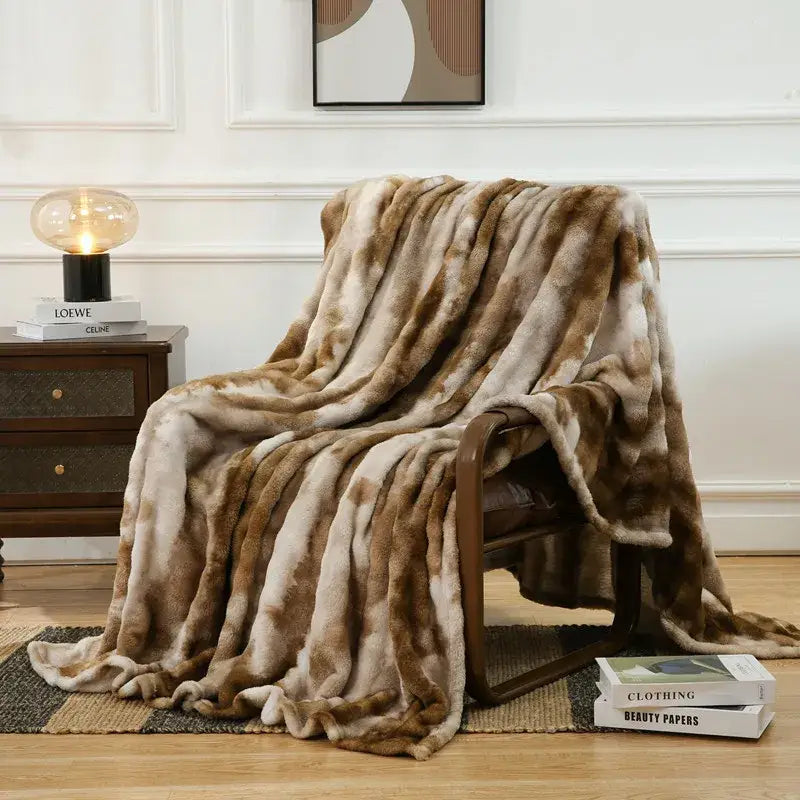 A mottled brown and cream decorbites fuzzy faux fur blanket draped over an armchair for bedroom and living room decor