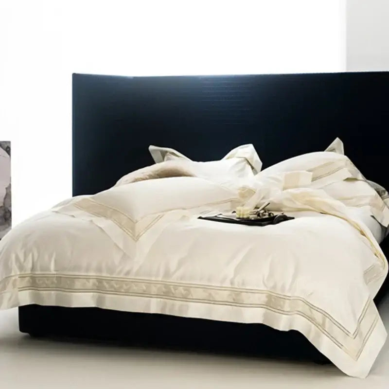 Cream gold satin bedding set with wide gold-threaded embroidery edges draped on black bed by decorbites in two sizes