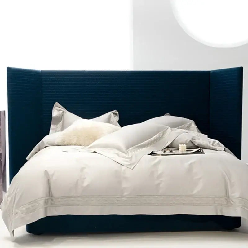 Deep blue upholstered bed with tall structured headboard and white cream gold embroidery decorbites bedding set two sizes