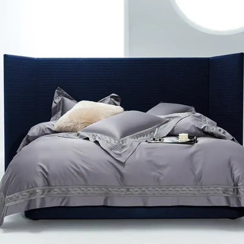 Luxury gray satin bedding set with intricate silver embroidery displayed on deep navy headboard by decorbites in two sizes