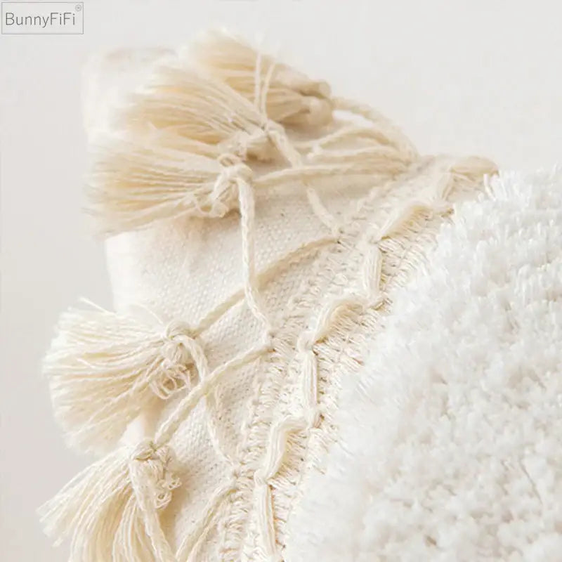 Cream-colored woven pillow cover with ivory pompom tassel and fluffy white fabric accents for living room decorbites decor