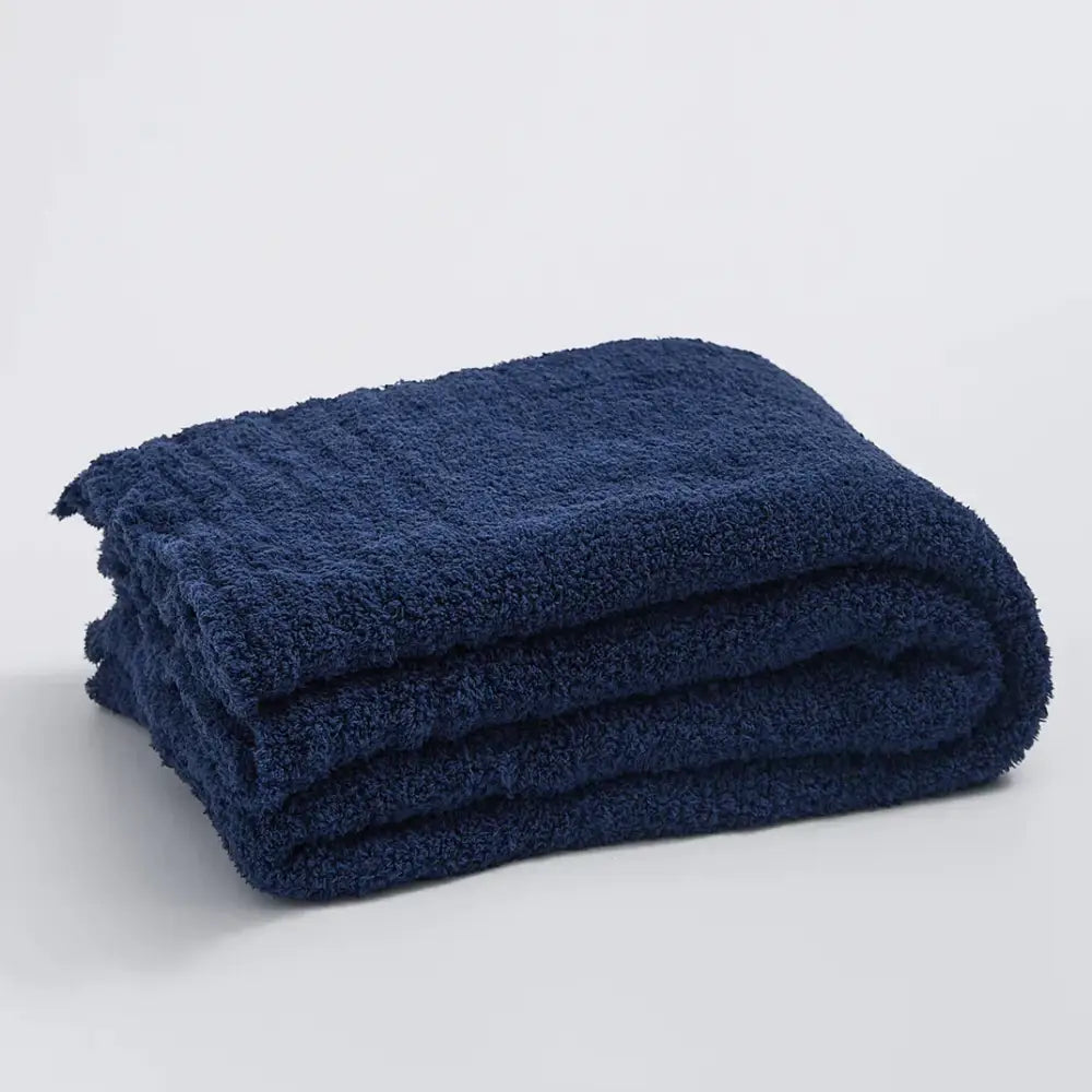 A plush deep navy blue knitted throw blanket with a soft textured terry cloth surface for bedroom use