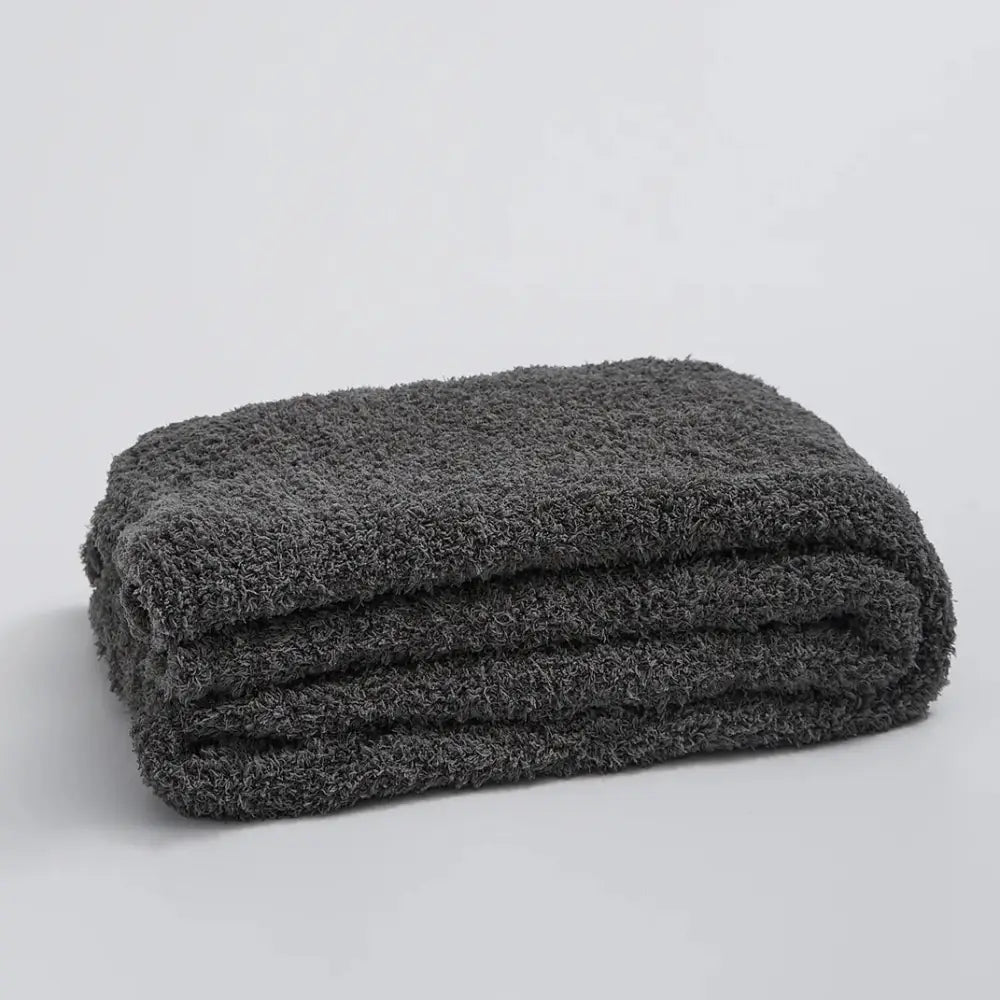 A plush dark gray knitted throw blanket with a soft ribbed microfiber surface suitable for bedroom use