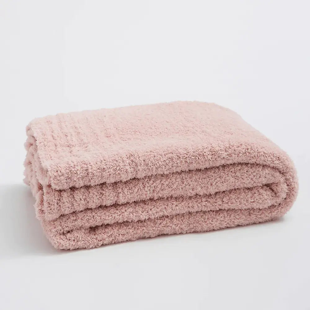 A dusty rose-colored plush knitted throw blanket with textured looped pile for cozy bedroom use