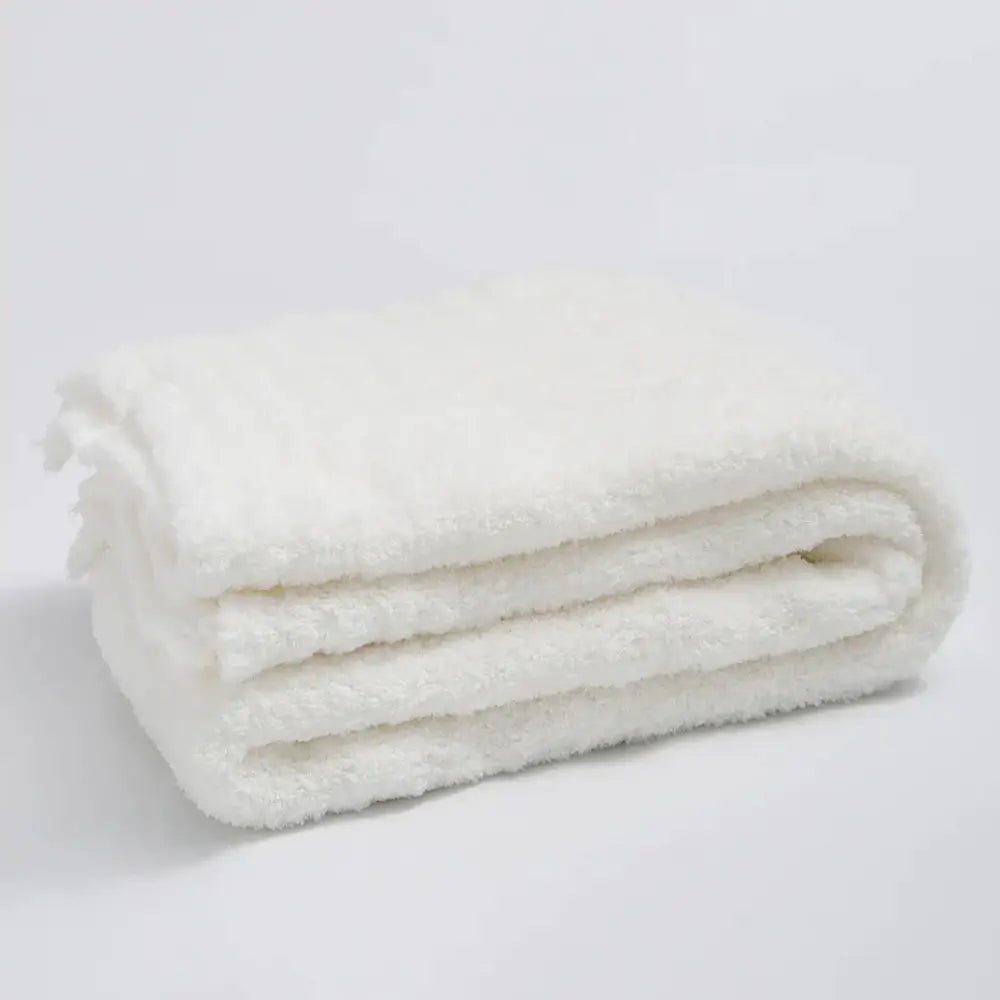 A plush white knitted throw blanket with a soft textured surface and ribbed microfiber edges for bedroom use