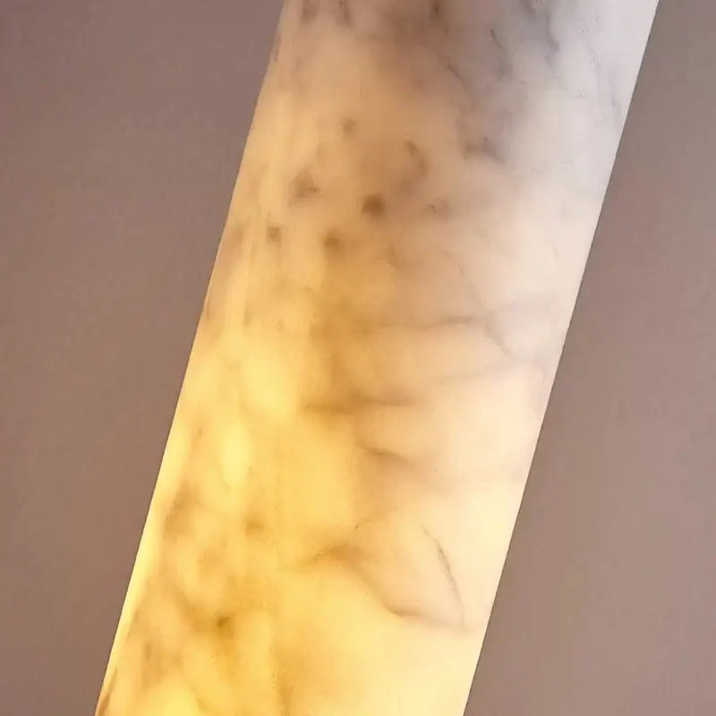 Cream marble cylinder pendant light with warm yellow glow and swirling gray veining for luxury bedroom decorbites cream marble