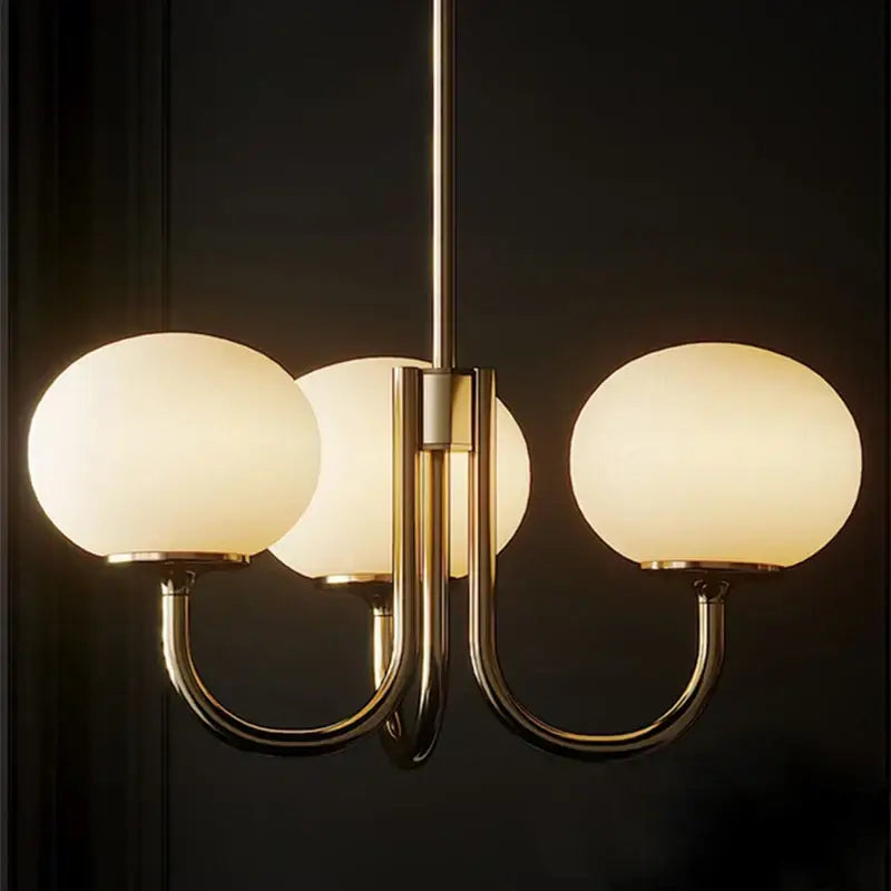 Gold-toned pendant light with three frosted glass globes for decorbites cream pink bedroom decor