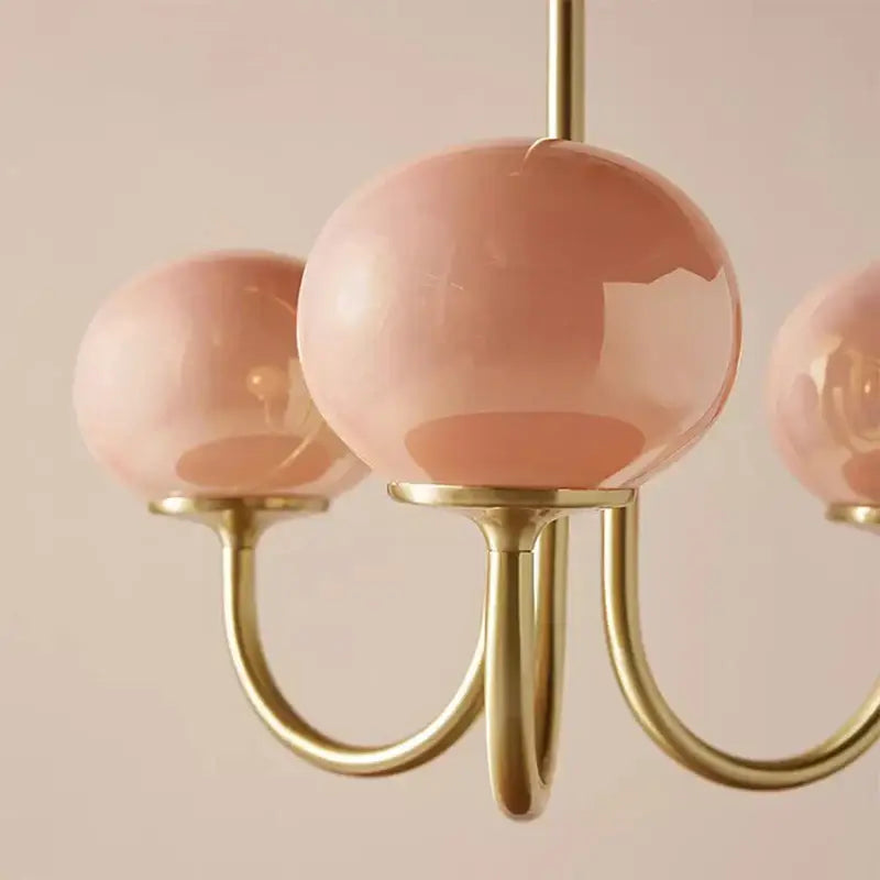 A cream pink bedroom pendant light with three blush pink glass globes and slender brass arms decorbites cream pink