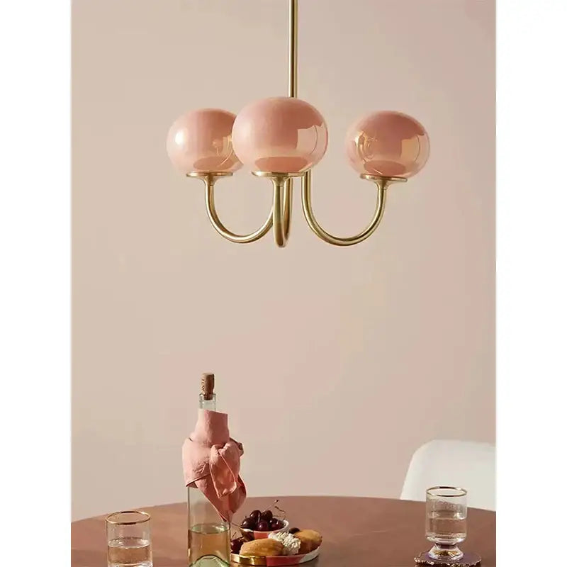 Delicate cream pink bedroom pendant light with three soft pink glass globes and polished brass accents by decorbites