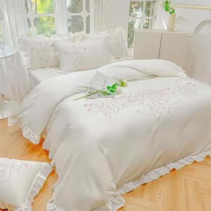 Cream and pink ice silk duvet set with white satin, embroidered ruffles, lace trim, and delicate pink bow designs